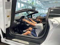 a young boy sitting in the driver's seat of a lamborghini